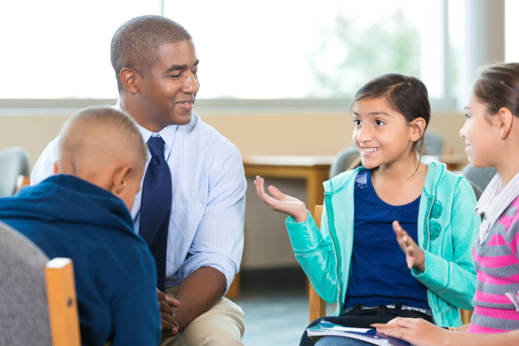 Elementary Age Kids Talking To Counselor During Group Therapy Session 